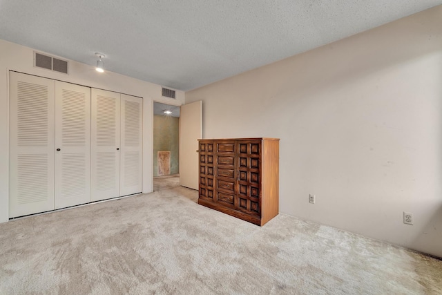 unfurnished bedroom with a closet, visible vents, carpet flooring, and a textured ceiling