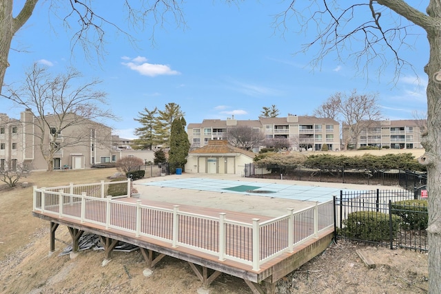 exterior space featuring a deck, a patio area, a community pool, and fence