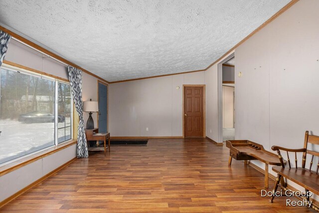 living area with a textured ceiling, wood finished floors, and ornamental molding