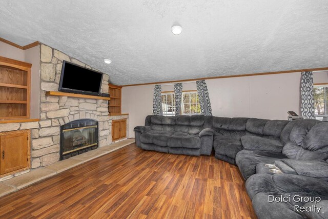 living room with a textured ceiling, wood finished floors, a fireplace, and crown molding