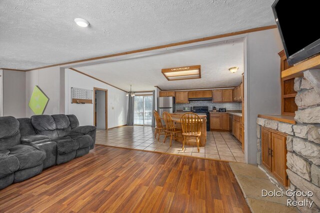 living room featuring a textured ceiling, vaulted ceiling, light wood finished floors, and ornamental molding