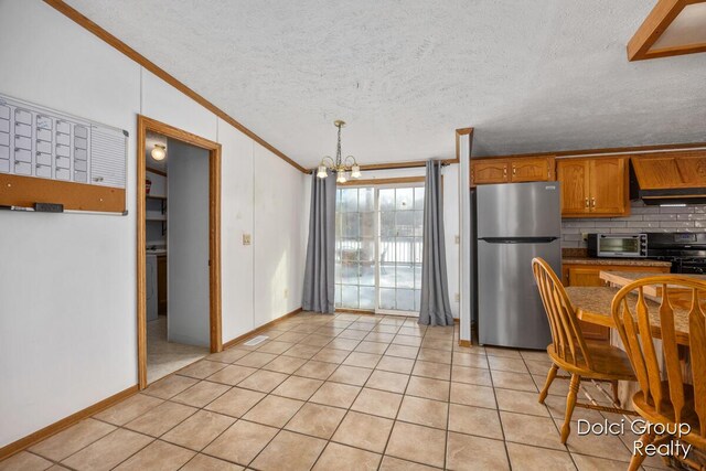 kitchen featuring crown molding, decorative backsplash, freestanding refrigerator, brown cabinetry, and range