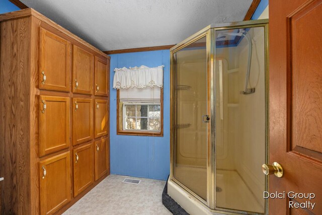 bathroom with a shower stall, visible vents, and a textured ceiling