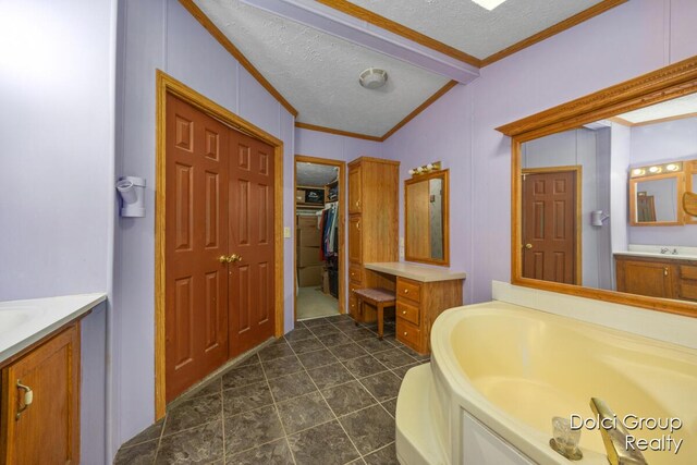 bathroom featuring vanity, lofted ceiling with beams, a textured ceiling, crown molding, and a bath