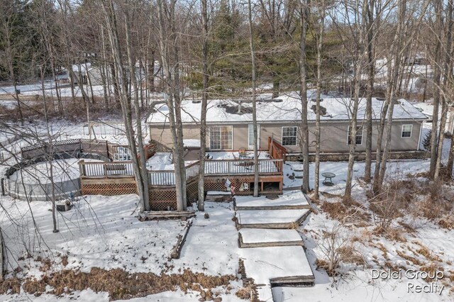 snow covered rear of property featuring a deck