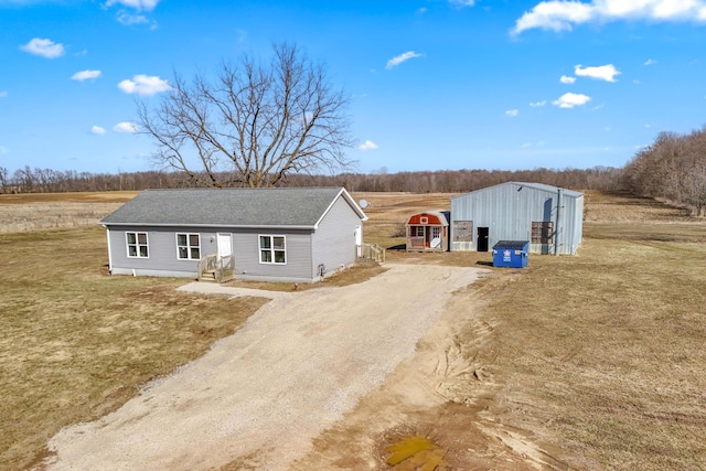 view of front of property featuring an outbuilding, driveway, an outdoor structure, and a front lawn