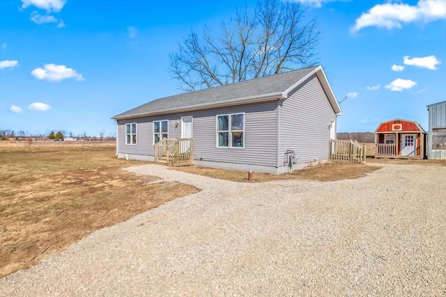 view of front facade featuring a storage shed, gravel driveway, and an outdoor structure