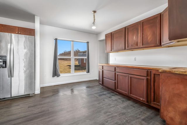 kitchen with dark wood finished floors, stainless steel fridge, light countertops, and baseboards