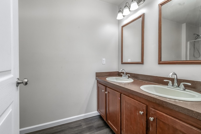 bathroom featuring a sink, baseboards, wood finished floors, and double vanity