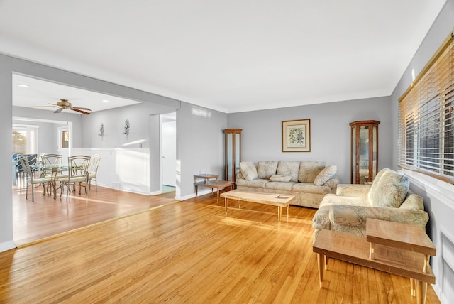 living room with baseboards, ceiling fan, and light wood finished floors