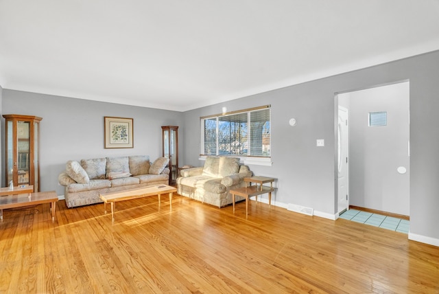 living area with visible vents, baseboards, and wood finished floors