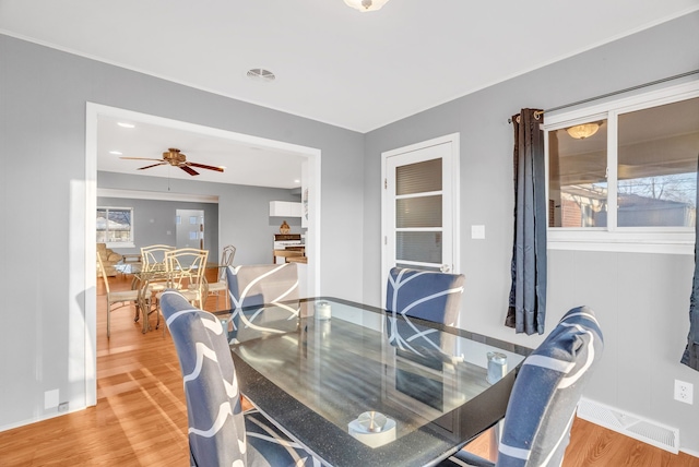 dining room with a ceiling fan, wood finished floors, visible vents, and baseboards