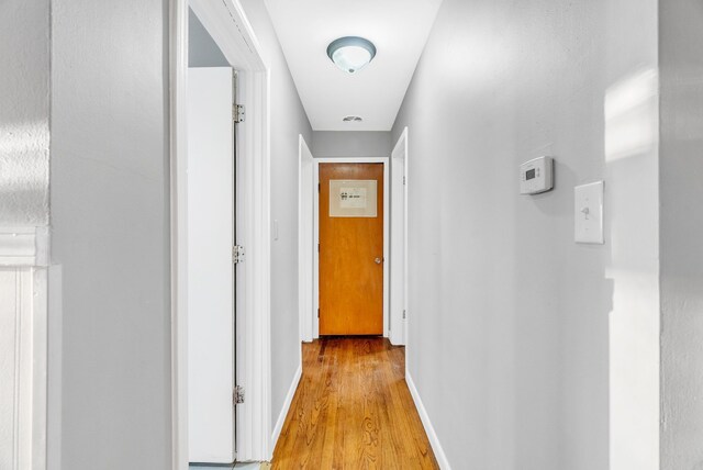 hallway featuring light wood finished floors and baseboards