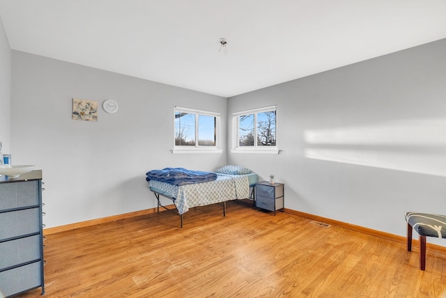 bedroom with visible vents, baseboards, and wood finished floors