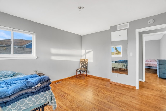 bedroom with visible vents, multiple windows, and light wood-style floors