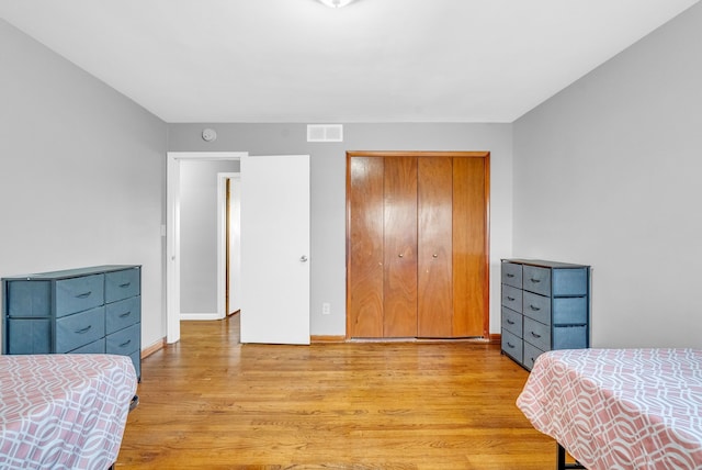 bedroom featuring a closet, baseboards, visible vents, and light wood finished floors