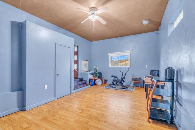 workout area featuring light wood-type flooring and a ceiling fan