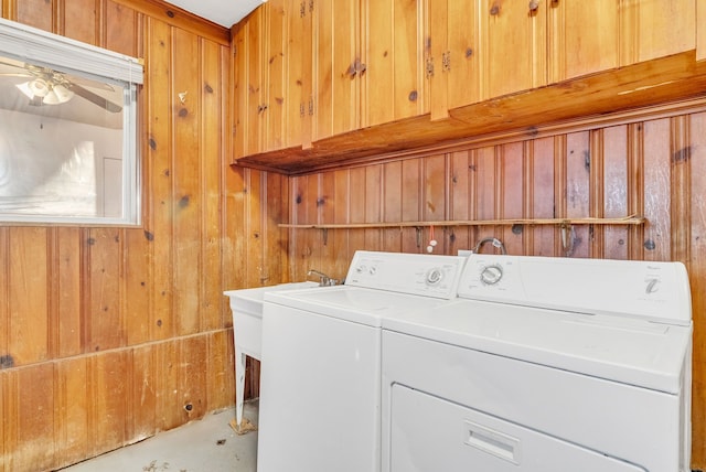 clothes washing area featuring ceiling fan, wood walls, laundry area, and washer and clothes dryer