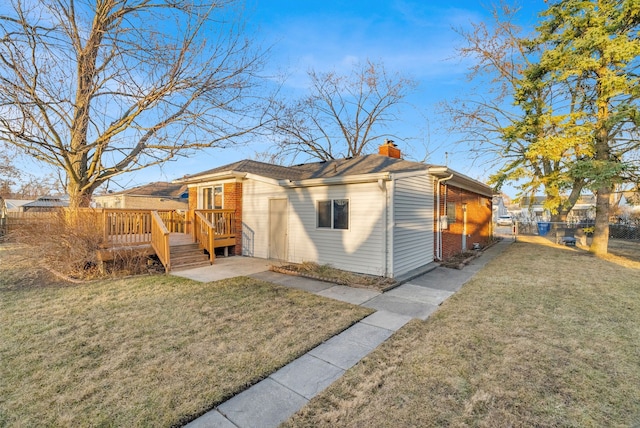 rear view of property with a lawn, a chimney, a deck, and fence