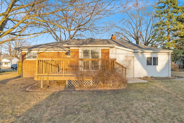 back of house featuring a deck, a lawn, brick siding, and a chimney