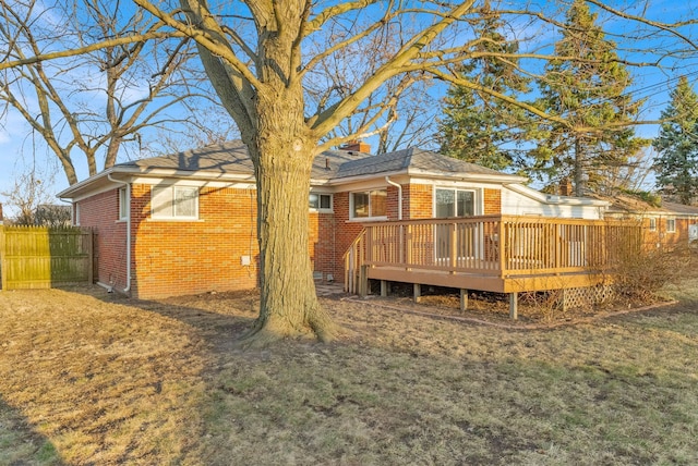 back of house with a deck, a yard, fence, and brick siding