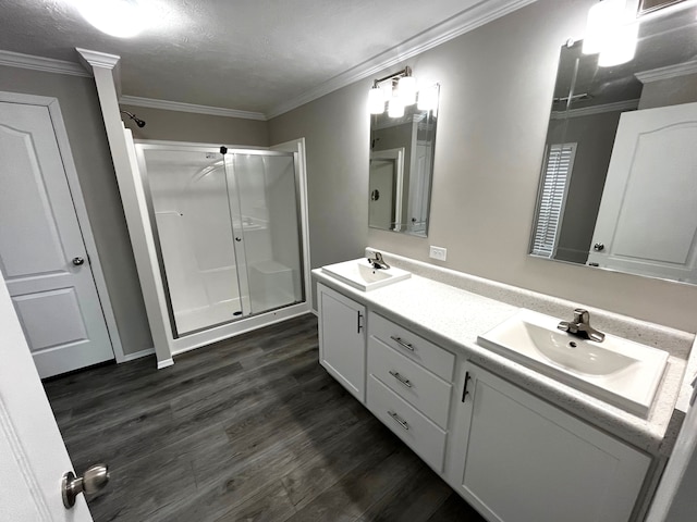 bathroom with a shower stall, wood finished floors, ornamental molding, and a sink