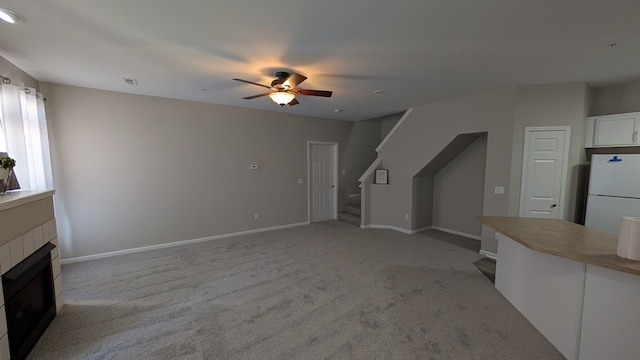 unfurnished living room featuring visible vents, baseboards, stairs, light carpet, and a fireplace