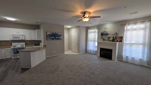 kitchen featuring visible vents, a tiled fireplace, open floor plan, white appliances, and ceiling fan