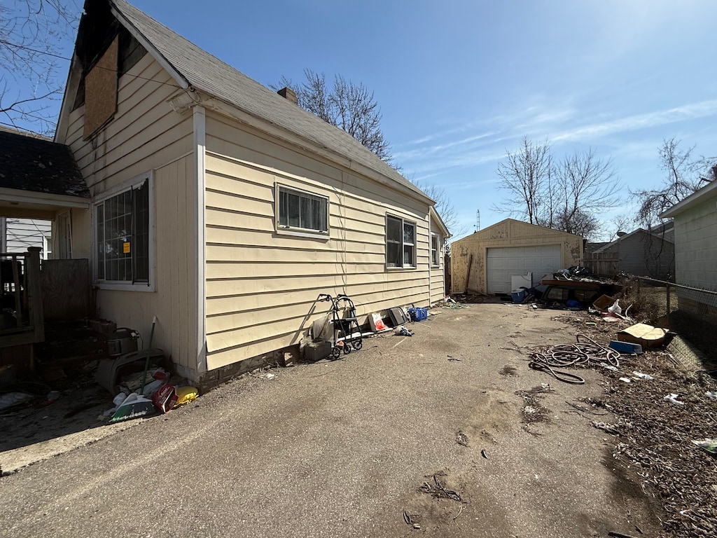 view of side of home featuring an outbuilding, fence, a garage, and driveway