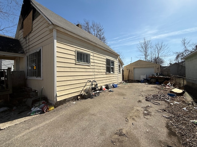 view of side of home featuring an outbuilding, fence, a garage, and driveway