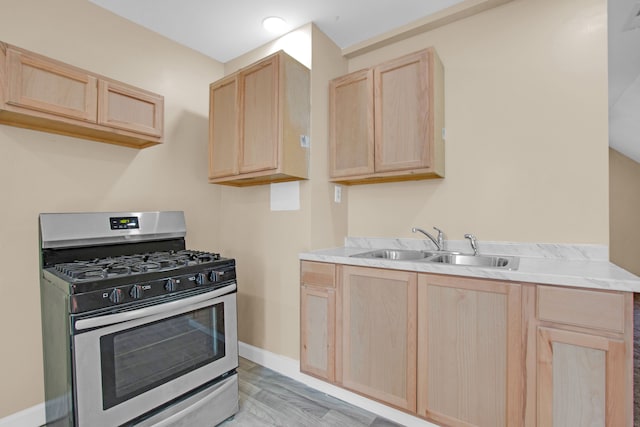 kitchen featuring a sink, stainless steel range with gas stovetop, light brown cabinetry, and light countertops