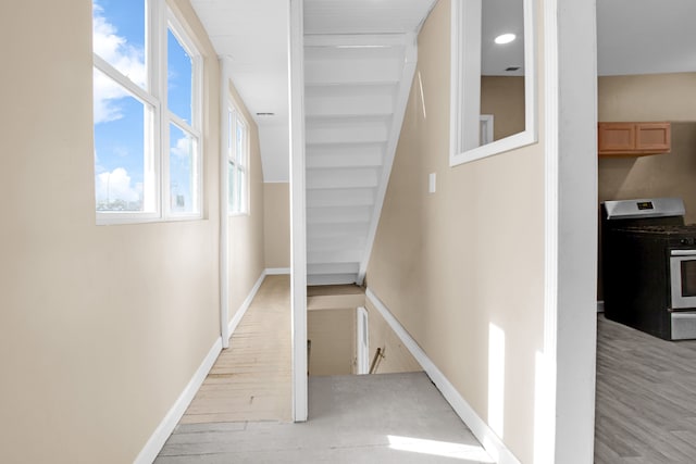 hallway with plenty of natural light, baseboards, and light wood-style floors