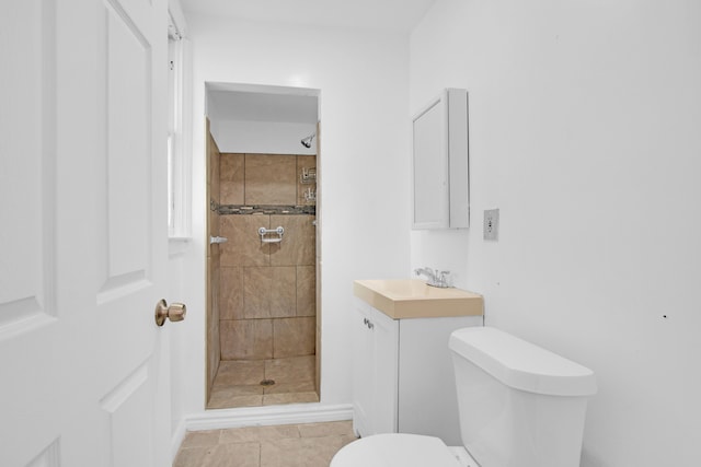 bathroom featuring toilet, vanity, and a tile shower