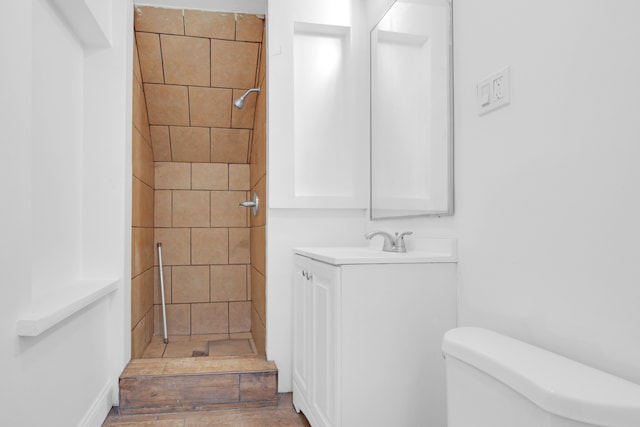 full bathroom with vanity, toilet, and tiled shower