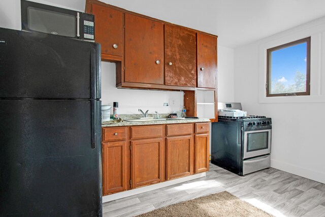 kitchen featuring black appliances, baseboards, brown cabinets, and a sink