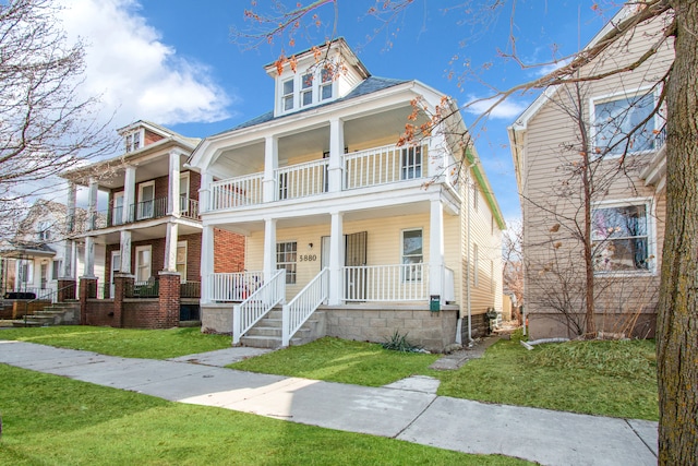 view of front of house featuring a balcony, a porch, and a front lawn