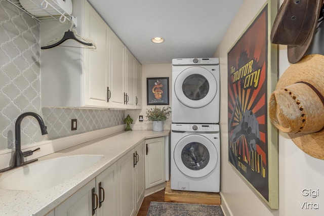 washroom with recessed lighting, cabinet space, stacked washer / drying machine, and a sink