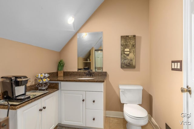 bathroom with vanity, baseboards, vaulted ceiling, tile patterned floors, and toilet