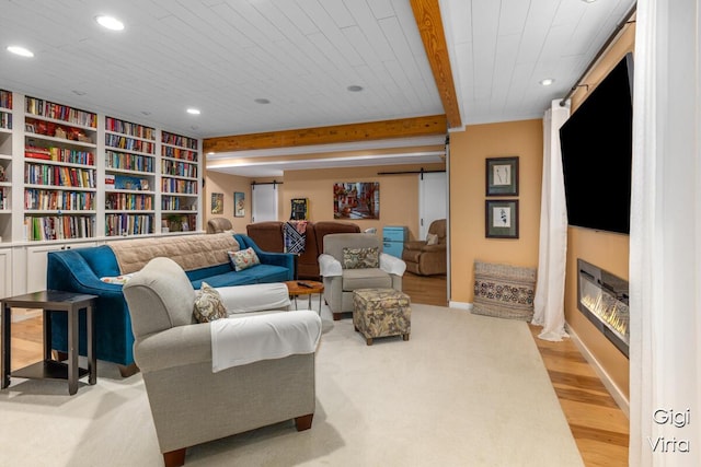 living room featuring a barn door, beam ceiling, recessed lighting, a fireplace, and light wood-style floors