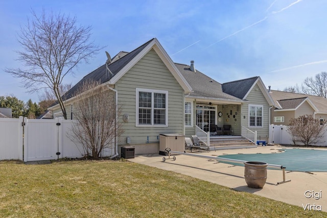 rear view of property featuring a gate, a fenced backyard, a yard, a fenced in pool, and a patio area