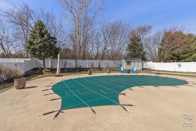 view of swimming pool featuring a fenced in pool, a fenced backyard, a patio area, a storage unit, and an outbuilding