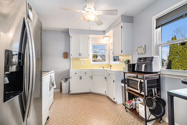 kitchen with white cabinetry, stainless steel appliances, light countertops, decorative backsplash, and ceiling fan