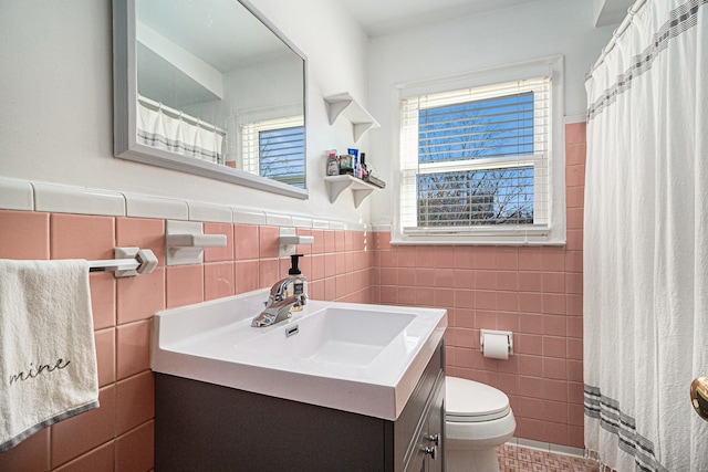 full bathroom with wainscoting, vanity, toilet, and tile walls