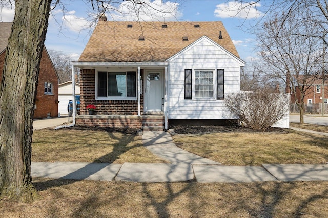 view of front of property featuring an outbuilding, roof with shingles, and a front yard