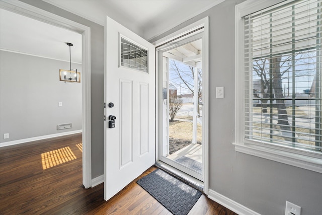 foyer featuring baseboards, a notable chandelier, dark wood-style floors, and crown molding