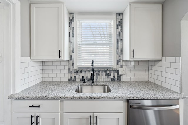 kitchen featuring tasteful backsplash, white cabinets, stainless steel dishwasher, and a sink