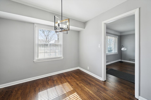 unfurnished dining area with an inviting chandelier, dark wood-type flooring, and baseboards