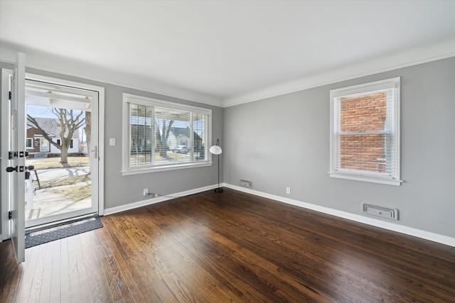 spare room featuring baseboards, dark wood finished floors, and crown molding