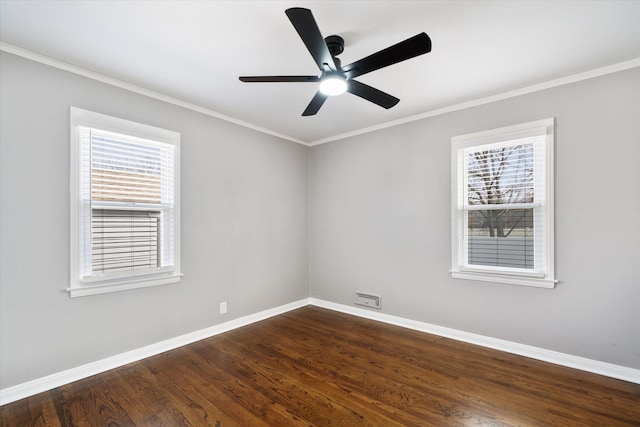 spare room featuring a wealth of natural light, dark wood-style floors, baseboards, and ornamental molding