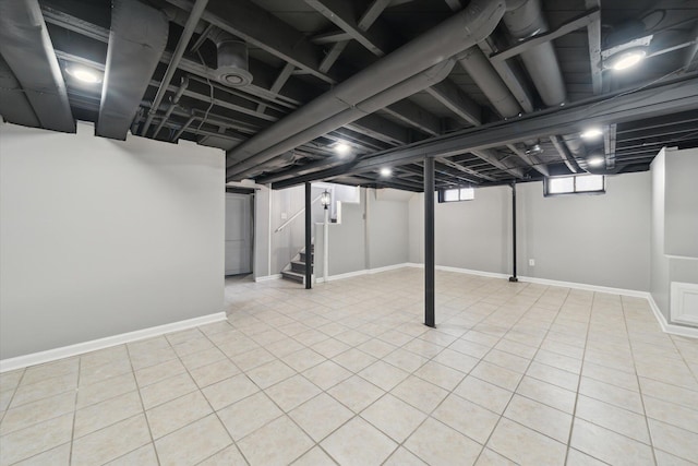 basement featuring tile patterned floors, stairs, and baseboards